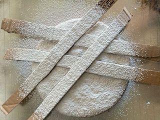 Un cerchio ricoperto di zucchero a velo e bastoncini di zucchero su un tavolo.