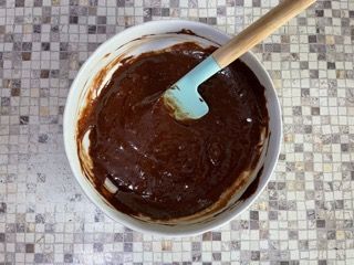 Una ciotola di impasto al cioccolato con una spatola dentro.