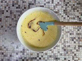 Una ciotola di liquido con una spatola dentro su un tavolo.