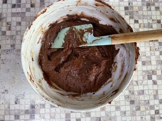 Una ciotola di impasto al cioccolato con una spatola dentro.