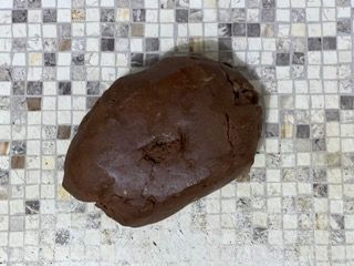 Un pezzo di pasta al cioccolato è appoggiato su un bancone piastrellato.