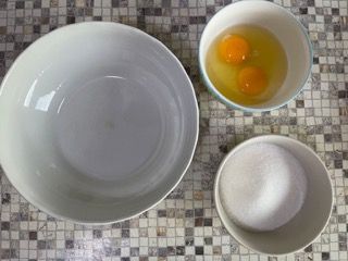 Ci sono tre ciotole di uova e zucchero su un tavolo.