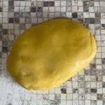 Un pezzo di pasta gialla è appoggiato su un tavolo.