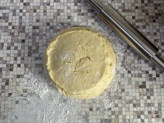 Un pezzo di pasta è appoggiato su un tavolo accanto a un mattarello.