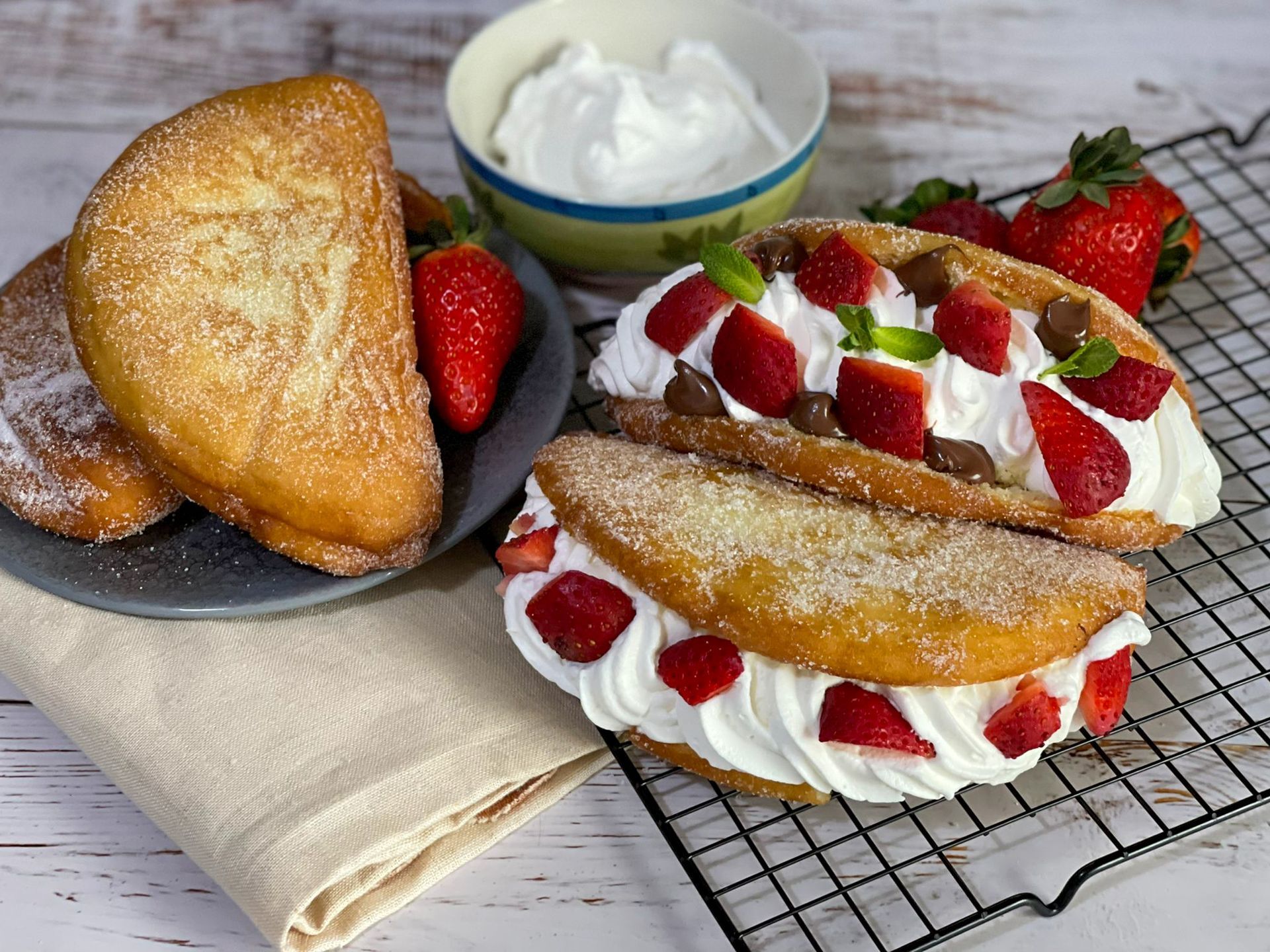 Due pasticcini con panna montata e fragole su un tavolo.