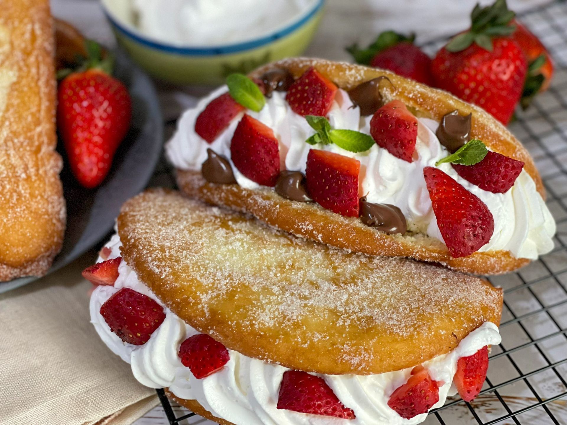 Un primo piano di un panino con panna montata e fragole su un tavolo.