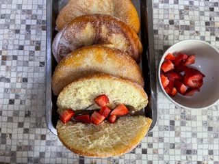 Un vassoio di pasticcini con fragole sopra accanto a una ciotola di fragole.