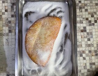 Un pezzo di cibo è posto in una padella ricoperta di zucchero.