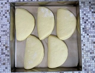 Quattro pezzi di pasta sono adagiati in una teglia di metallo