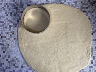 Un pezzo di pasta viene tagliato a forma di cerchio su un tavolo.