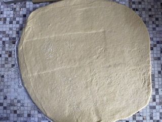 Un grosso pezzo di pasta è appoggiato su un tavolo piastrellato.