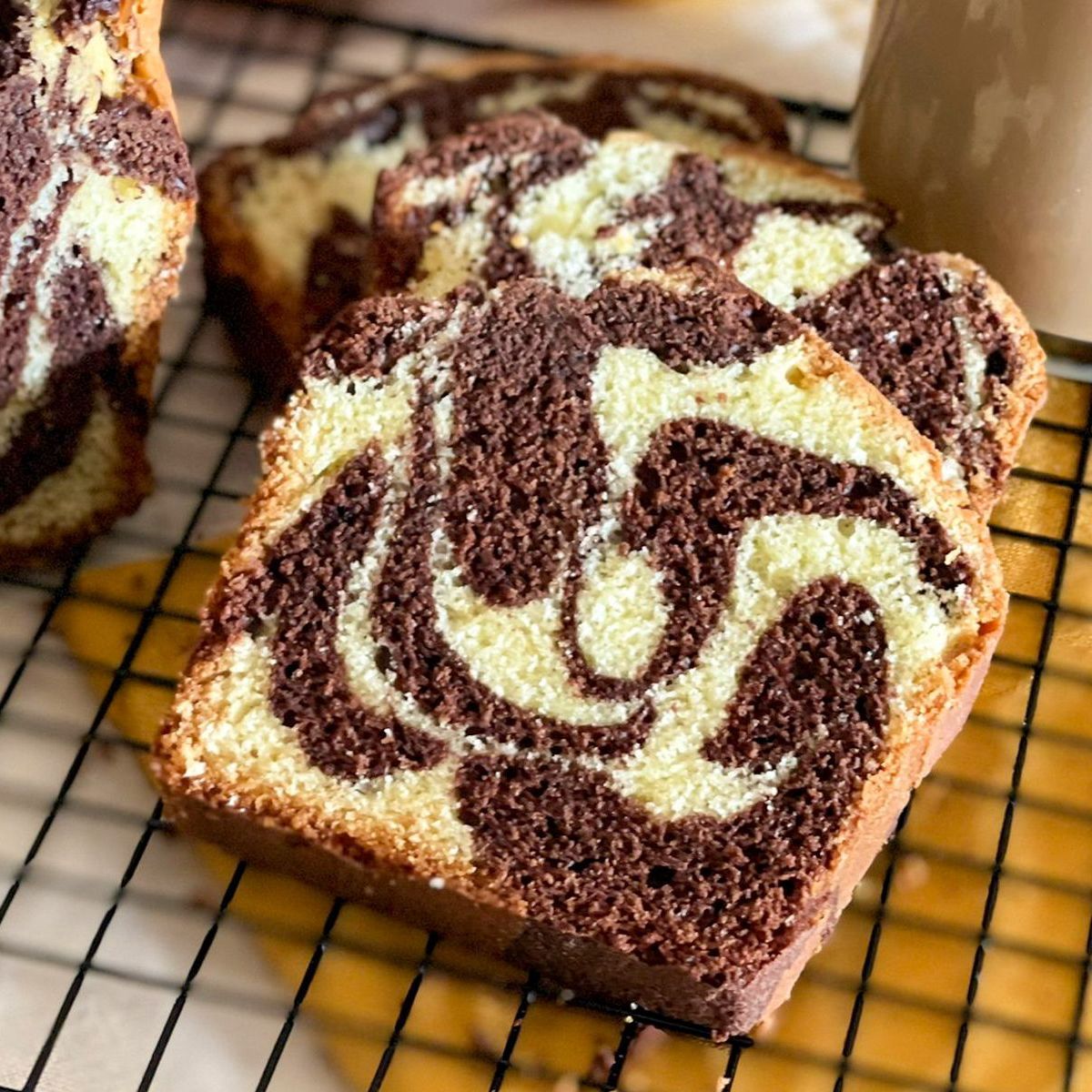Due fette di plumcake al cioccolato e marmo bianco sono adagiate su una griglia di raffreddamento.