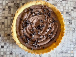 Su un tavolo c'è una torta al cioccolato con gocce di cioccolato sopra.