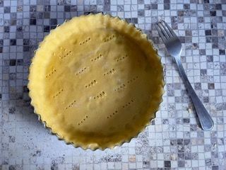 Una pasta per torta è appoggiata su un tavolo accanto a una forchetta.