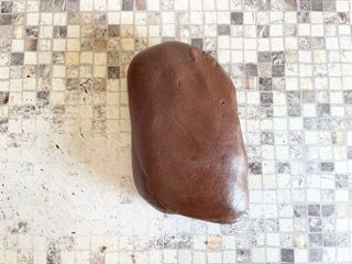 Un grosso pezzo di pasta al cioccolato è appoggiato su un bancone piastrellato.