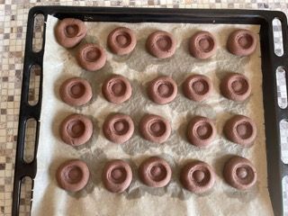 Un vassoio di ciambelle al cioccolato appoggiato su un foglio di carta oleata.