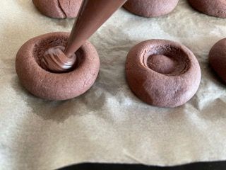 Una persona sta versando il cioccolato in un biscotto con una sac à poche.