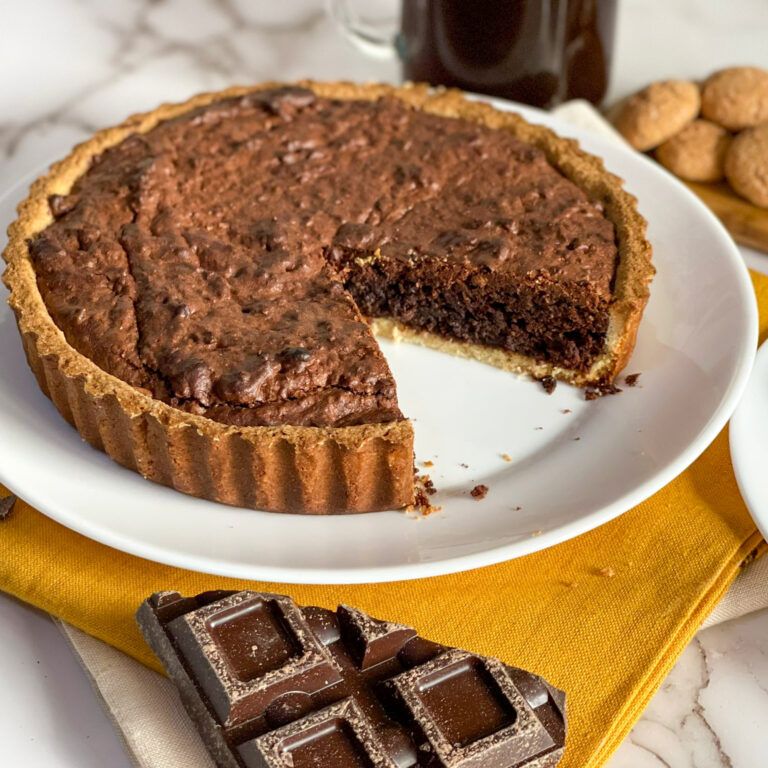 Una torta al cioccolato con una fetta staccata è su un piatto bianco.