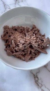 Una ciotola bianca piena di cioccolato tritato su un tavolo.