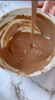 Una persona sta versando la salsa al cioccolato in una ciotola.