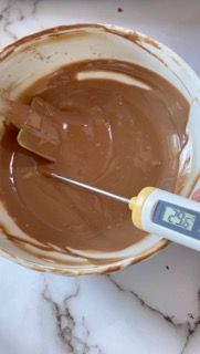 Un termometro viene utilizzato per misurare la temperatura di una ciotola di cioccolato.