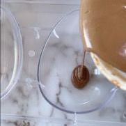 Primo piano di una persona che versa del cioccolato in un bicchiere.