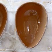 Due uova di cioccolato sono appoggiate una sopra l'altra su un tavolo.