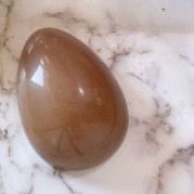 Un uovo marrone è appoggiato su una superficie di marmo bianco.