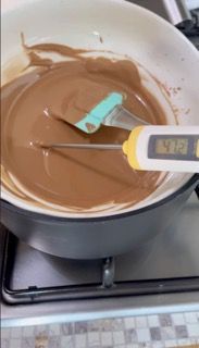 Si utilizza un termometro per misurare la temperatura del cioccolato in una padella.