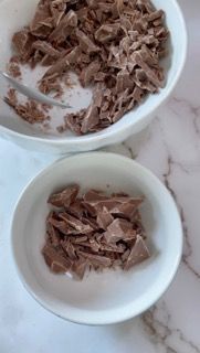 Una ciotola di cioccolato tritato accanto a una ciotola più piccola di cioccolato tritato.