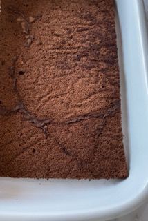 Primo piano di una fetta di torta al cioccolato in una teglia bianca.