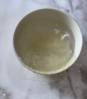 Una ciotola bianca piena di liquido è appoggiata su un tavolo.