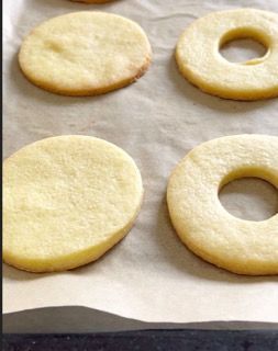 Quattro biscotti con i buchi sono su un pezzo di carta oleata