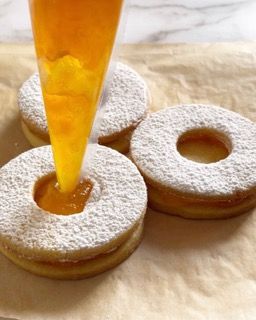 Un biscotto con un buco nel mezzo viene ricoperto di zucchero a velo.