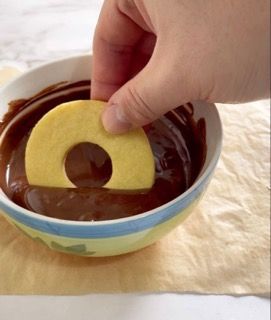 Una persona sta immergendo una mela in una ciotola di cioccolato