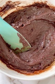 Una ciotola di glassa al cioccolato con una spatola dentro.
