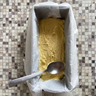 Uno stampo da plumcake pieno di pastella e un cucchiaio dentro