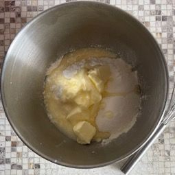 Una ciotola di metallo piena di burro, zucchero e una frusta.