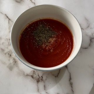 Una ciotola di zuppa di pomodoro è appoggiata su un tavolo di marmo.