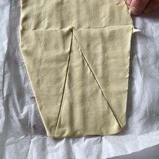 Una persona tiene in mano un pezzo di pasta su un foglio di carta oleata.