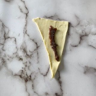 Un pezzo di pasta con sopra del cioccolato si trova su una superficie di marmo.