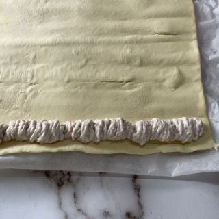 Un pezzo di pasta con sopra della panna montata è appoggiato su un tavolo.