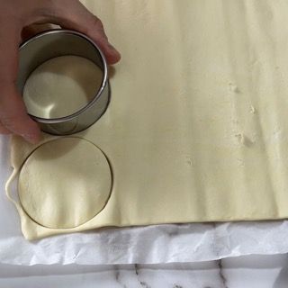 Una persona sta ritagliando un cerchio da un pezzo di pasta.