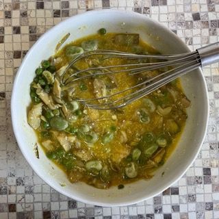 Una ciotola di cibo con una frusta dentro su un tavolo.