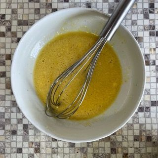 Una ciotola di liquido giallo con una frusta dentro