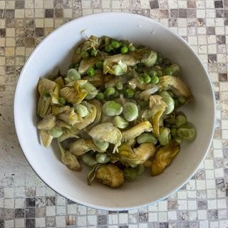 Una ciotola bianca piena di carciofi e piselli verdi
