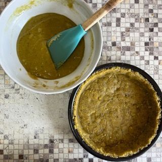 Una ciotola di salsa accanto a una teglia di pasta per torta