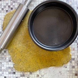 Un mattarello è appoggiato su un pezzo di pasta accanto a una padella