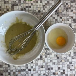 Una ciotola di liquido accanto a una ciotola con un uovo e una frusta.