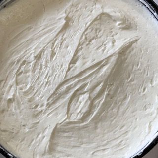 Un primo piano di una ciotola di glassa bianca con un cucchiaio dentro